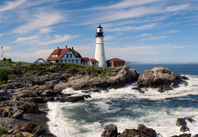 New England lighthouse with waves crashing on rocky shore